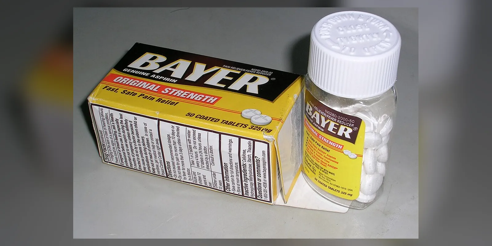 A bottle of Bayer brand coated aspirin tablets with a child-resistant cap bearing the instruction "push down &amp; turn to open".